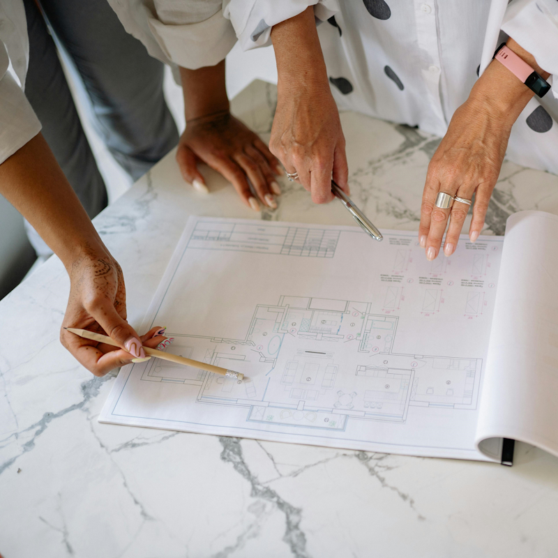 Image shows people looking at an arhitecture blueprint. Resources Insights Guides for Interior Designers and Architects on SEO Website Strategy and Growth Marketing