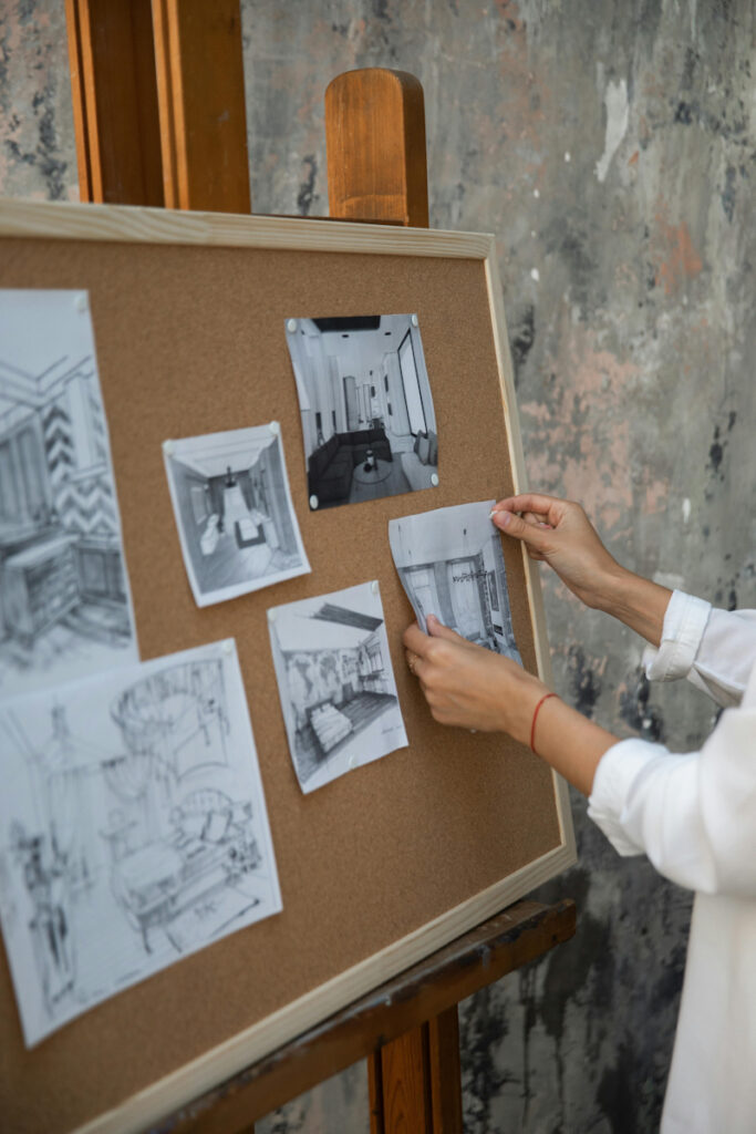 Woman hanging pictures of interior architecture projects on board. What Makes a Great Interior Design Portfolio Website in 2026 Blog Post
