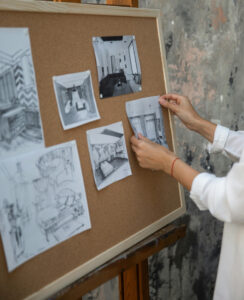 Woman hanging pictures of interior architecture projects on board. What Makes a Great Interior Design Portfolio Website in 2026 Blog Post